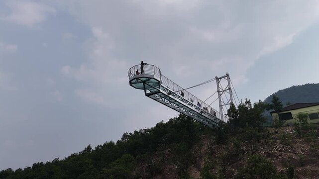 The Glass Bridge in Rajgir, Bihar, offers panoramic views of lush hills and valleys. Built with transparent tempered glass, it attracts tourists seeking adventure, scenic beauty, and elevated skywalk 