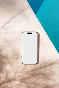 Phone mockup with white screen by pool outdoors