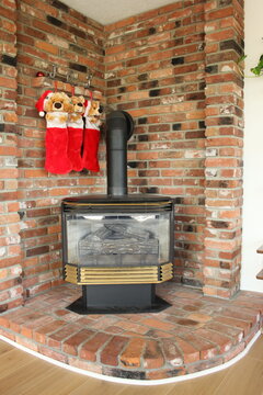 3 Stockings hung with JOY by brick fireplace