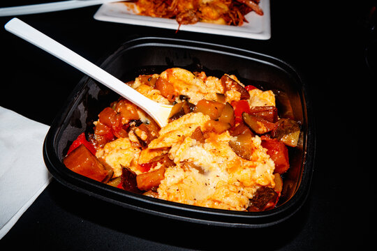 polenta with sauteed vegetables served in a black takeaway tray