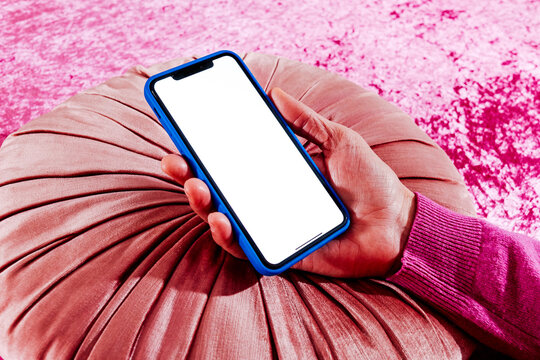 a man holds a smartphone with a blank screen over a velvet cushion