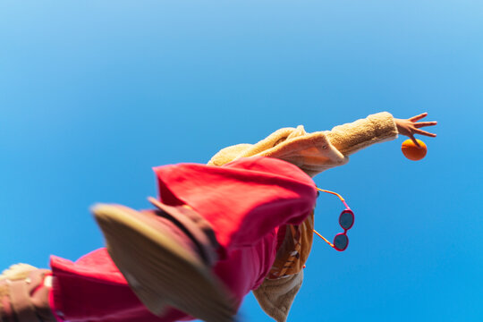 Low angle shot of girl jumping over to catch an orange