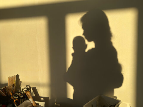 Shadow of a parent holding baby in a room