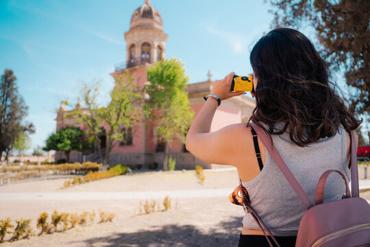 Woman taking a photograph of a historic palace with a compact camera