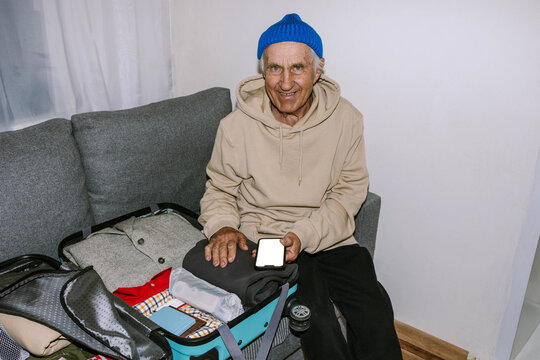 A man packs his suitcase by checking a list on his phone.