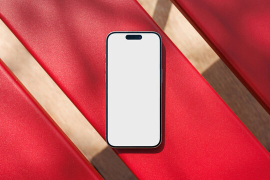 Phone mockup with white screen on red bench outdoors
