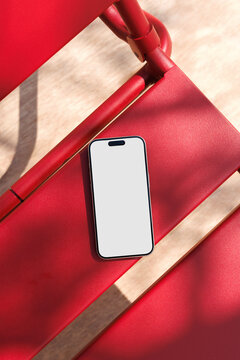 Phone mockup on red chair in summer sunlight