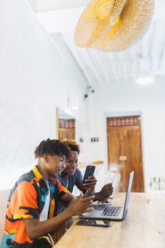 Young African friends connecting with technology in cafe