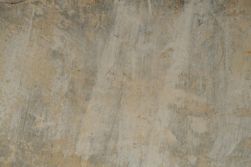Fototapeta premium Close-up of a weathered plastered wall with peeling and flaking paint in shades of beige, grey and ochre yellow, showing signs of age and decay