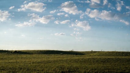 Obraz premium Rolling grass prairie under blue sky on open plain.