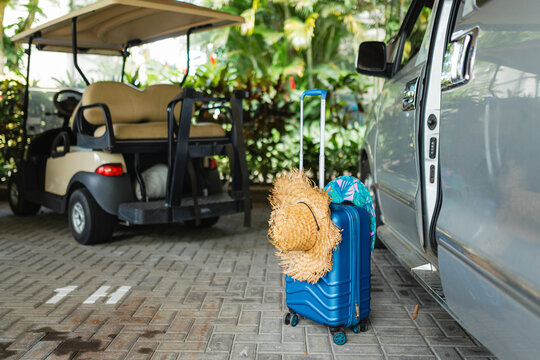 Blue Suitcase With Hat Next To Microbus In Covered Parking