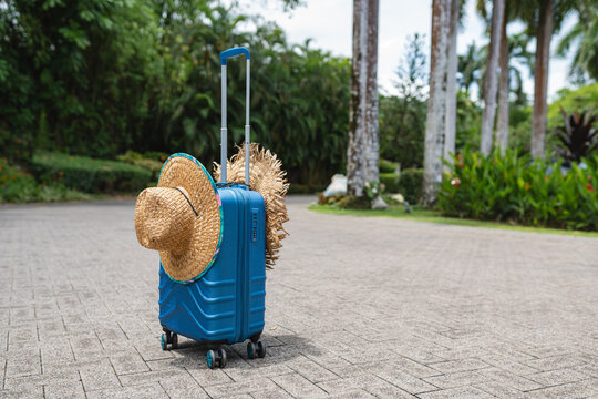 Blue Suitcase With Straw Hats On A Resort Path