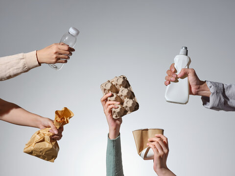 Hands holding recyclable items on gray background