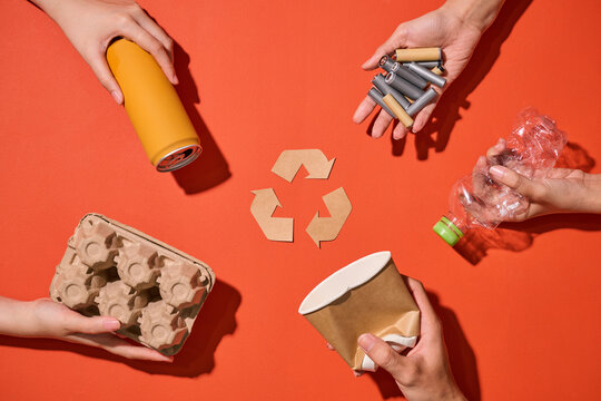 Hands demonstrate recycling by holding various recyclable items