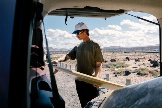 Surfer lifting a surfboard from a van, getting ready for surf session