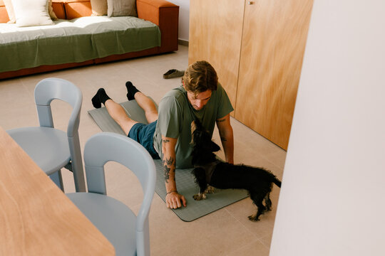 Contemporary man doing yoga with a dog in a modern designer apartment