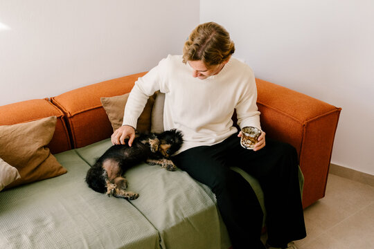 Single man sitting on modern armchair spending quiet time with his pet