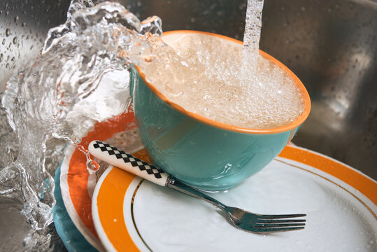 Water drains into a mug in the kitchen sink.