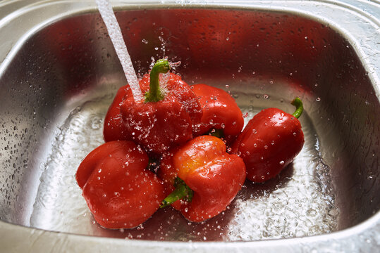 Washing red peppers in a kitchen sink
