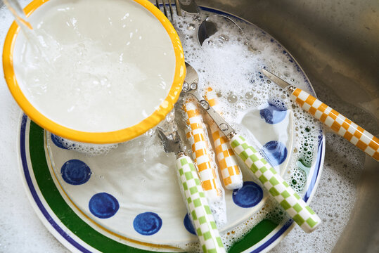 Washing dishes in a kitchen sink with soapy water