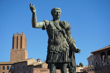 A bronze statue of the ancient Roman emperor Trajan stands in the Roman Forum, Foro Romanum, on a sunny day. © AlexanderRuszczynski