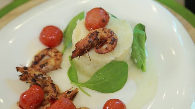 Plating and presentation of celery root puree with fried shrimp and cherry tomatoes