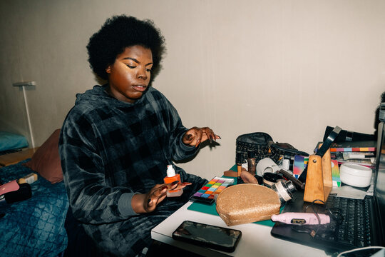 Person Applying Makeup in a Room With a Cluttered Table