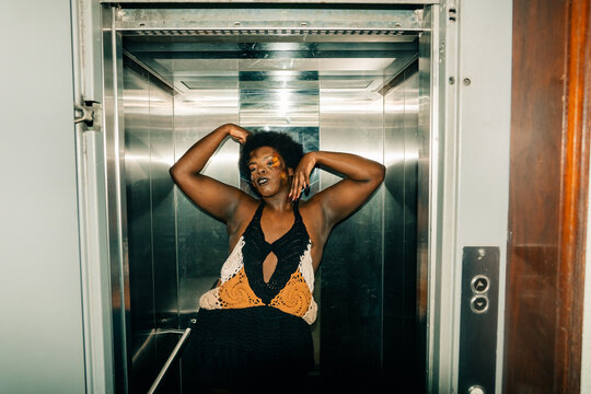 Person Poses Confidently in Elevator Wearing Colorful Outfit