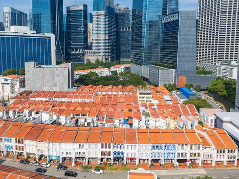 Lines of row houses with terracotta tiled roofs below city skyscapers