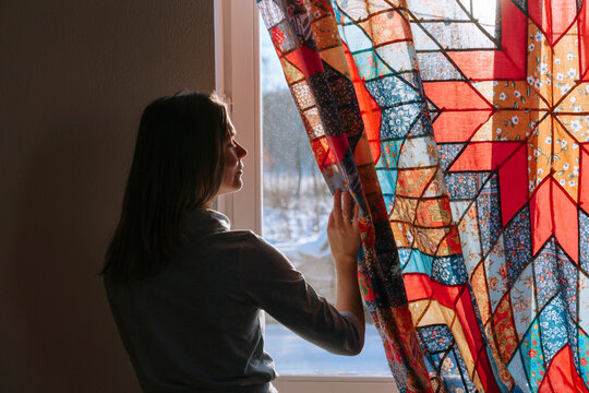 Bright Morning Light Streams Through Curtains as a Woman Looks Out