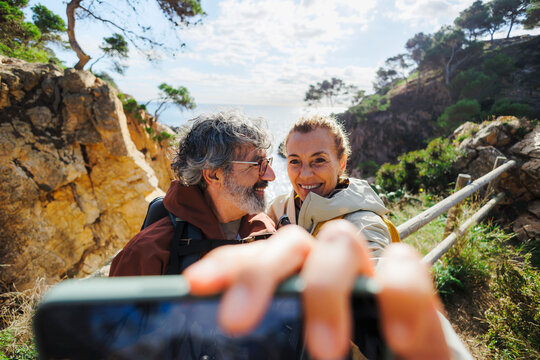 Couple taking selfie while hiking seaside