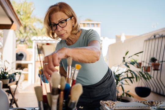 Senior woman painting a frame