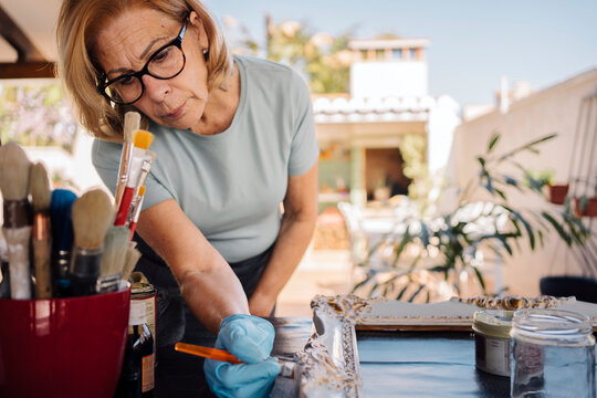 Senior woman painting a frame