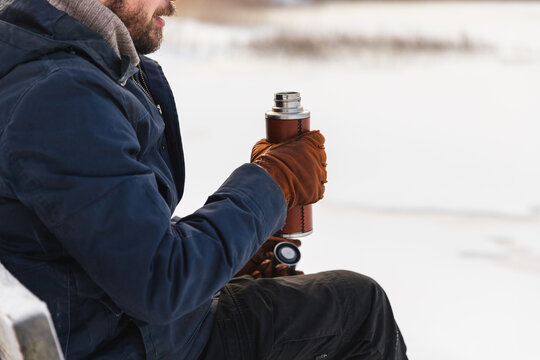 Close-up of man holding thermos with hot drink in winter