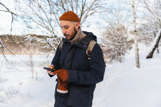 Man using smartphone in snowy winter landscape