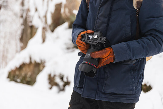 Close up of photographer holding professional camera in snow