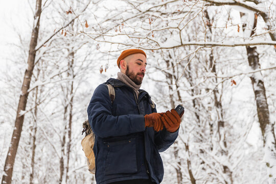 Man checking mobile phone for navigation in a winter snowy forest
