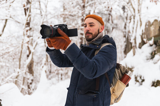 Professional photographer capturing winter landscape in snowy forest