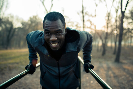 Smiling athlete doing tricep dips on outdoor bars in a winter park
