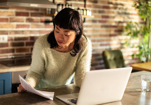 Woman reviewing documents while working from home in kitchen