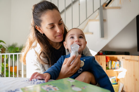 Mother helping baby with asthma inhaler treatment