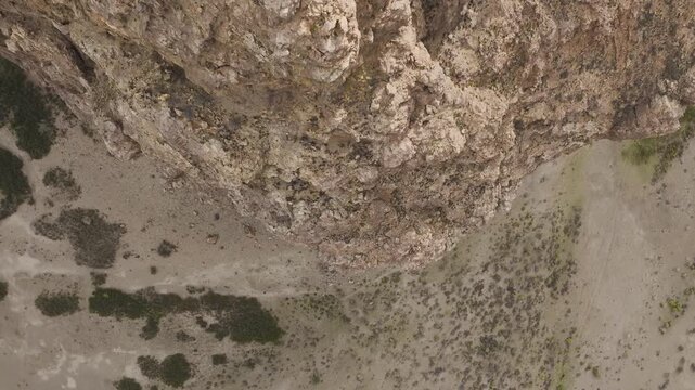 Zenith aerial shot of an individual walking across the highest point of a volcanic rock formation