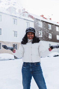 Joyful young woman with open arms celebrating the first snowfall