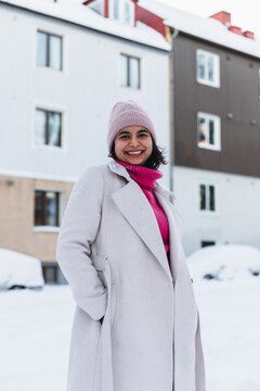 Portrait of a smiling young woman walking in a snowy urban park