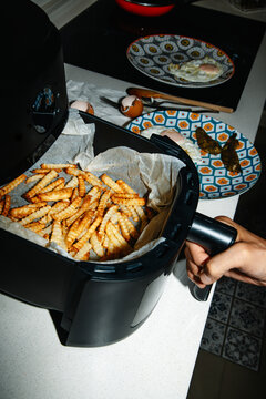 man preparing crinkle cut fries in an air fryer