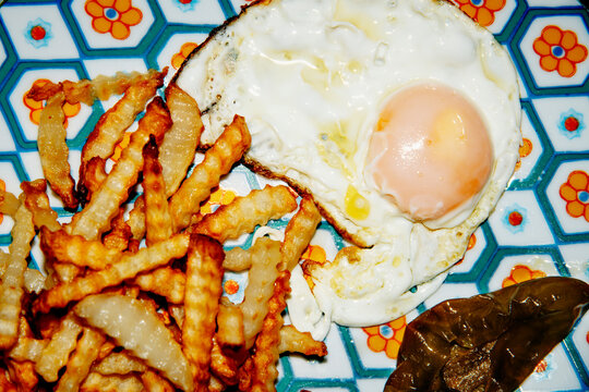 fried egg, crinkle cut potatoes and fried green peppers on a plate