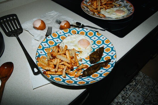 a plate with fried potatoes, egg and fried green peppers on a counter