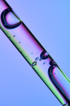 Close up of a pipette with face serum on clean blue background. 