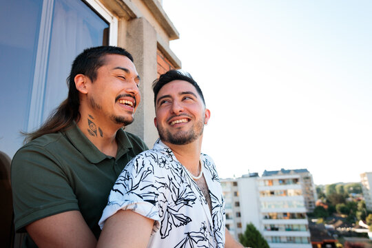 Gay Couple Smiling Together on Apartment Balcony