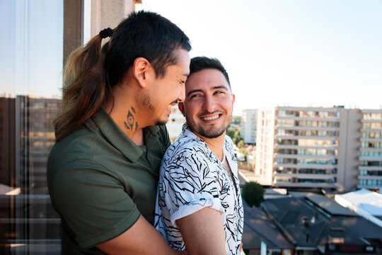 Gay Couple Embracing on Balcony of New Apartment